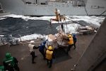 Sailors aboard the Arleigh Burke-class guided-missile destroyer USS Roosevelt (DDG 80) receive pallets of food stores during a replenishment-at-sea with the dry cargo ship USNS William McClean (T-AKE 12), April 1, 2021.
