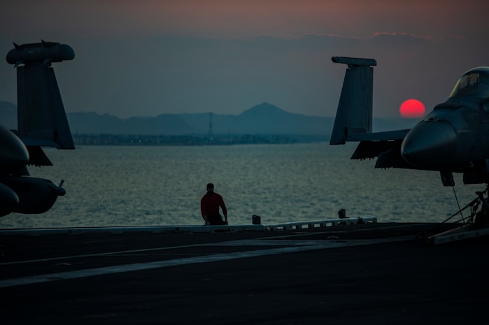 210402-N-OB471-2021 SUEZ CANAL (April 2, 2021) Aviation Boatswain's Mate (Handling) Airman Connor Schieffer watches from the flight deck as the aircraft carrier USS Dwight D. Eisenhower (CVN 69) transits the Suez Canal, April 2. The Eisenhower Carrier Strike Group is deployed to the U.S. 5th Fleet area of operations in support of naval operations to ensure maritime stability and security in the Central Region, connecting the Mediterranean and Pacific through the Western Indian Ocean and three strategic choke points. (U.S. Navy photo by Mass Communication Specialist Seaman Jacob Hilgendorf)