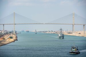 210402-N-EE423-1005 SUEZ CANAL (April 2, 2021) The guided-missile cruiser USS Monterey (CG 61), left, and the guided-missile destroyer USS Thomas Hudner (DDG 116) sail behind the aircraft carrier USS Dwight D. Eisenhower (CVN 69) during a Suez Canal transit, April 2. The Eisenhower Carrier Strike Group is deployed to the U.S. 5th Fleet area of operations in support of naval operations to ensure maritime stability and security in the Central Region, connecting the Mediterranean and Pacific through the Western Indian Ocean and three strategic choke points. (U.S. Navy photo by Mass Communication Specialist 2nd Class Sophie A. Pinkham)