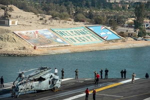 210402-N-FE499-2015 SUEZ CANAL (April 2, 2021) Sailors watch from the flight deck as the aircraft carrier USS Dwight D. Eisenhower (CVN 69) transits the Suez Canal, April 2. The Eisenhower Carrier Strike Group is deployed to the U.S. 5th Fleet area of operations in support of naval operations to ensure maritime stability and security in the Central Region, connecting the Mediterranean and Pacific through the Western Indian Ocean and three strategic choke points. (U.S. Navy photo by Mass Communication Specialist 3rd Class Andrew T. Waters)