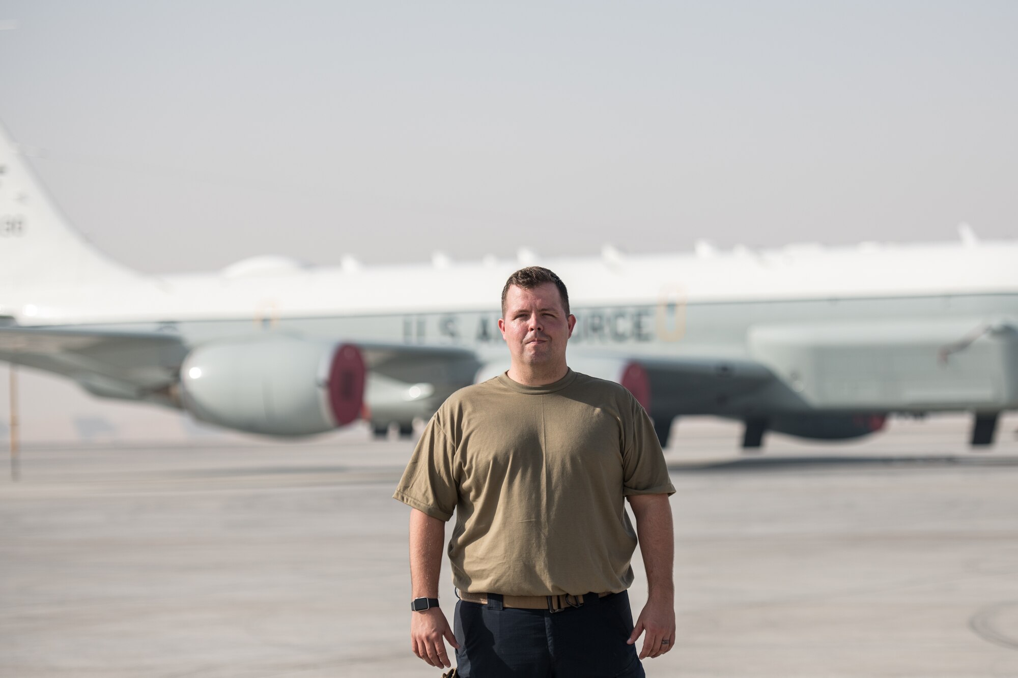 a man poses for a portrait in front of an airplane