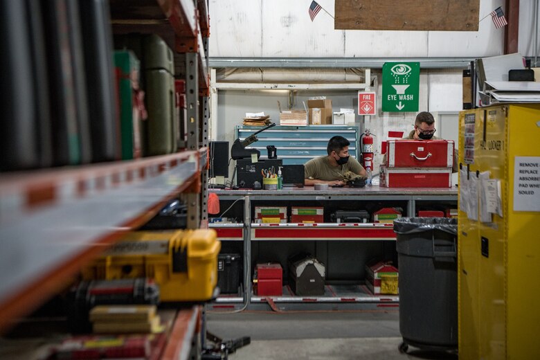 two men in a workshop examine a box of tools