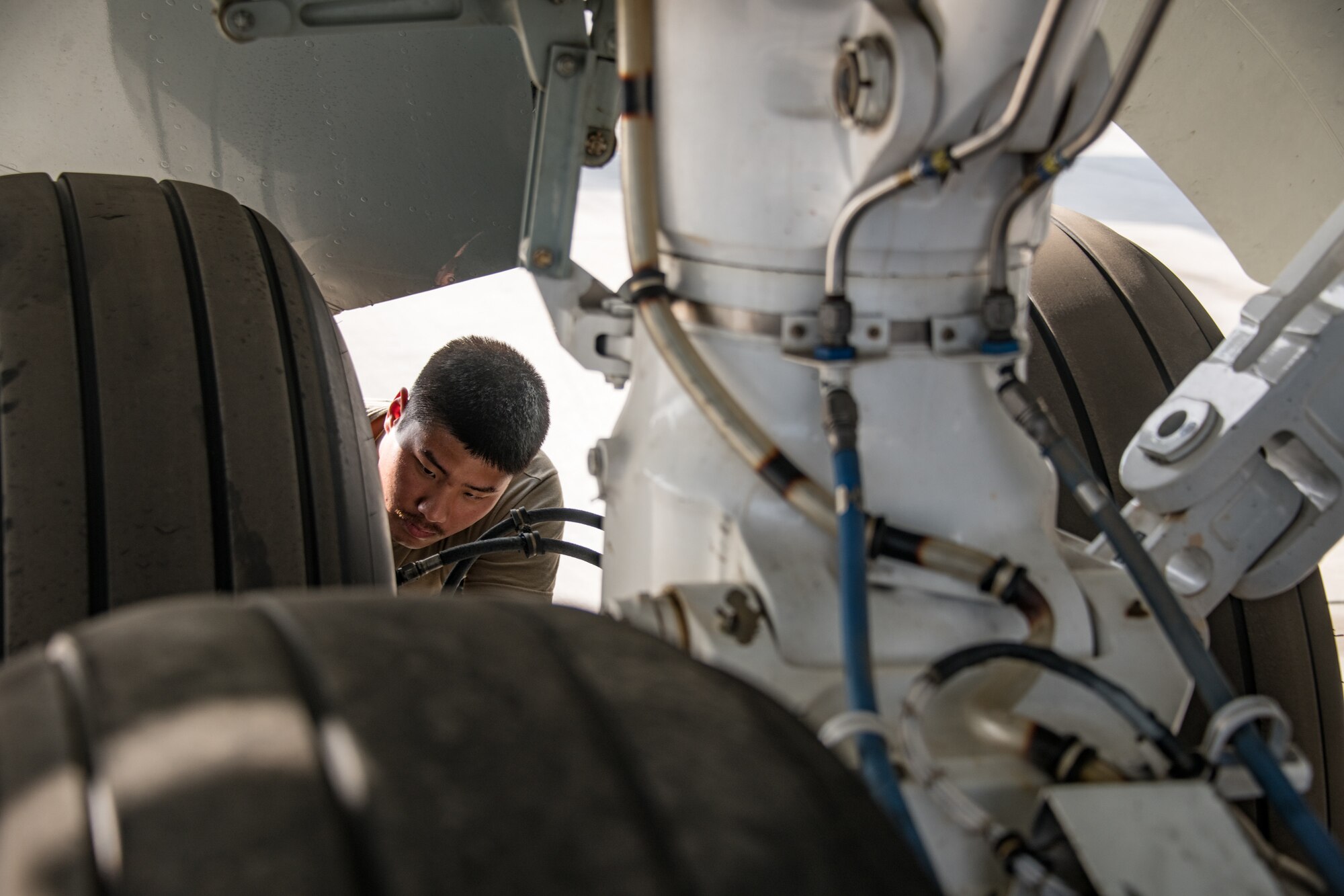 A man inspects the landing gear of an RC-135 Rivet Joint