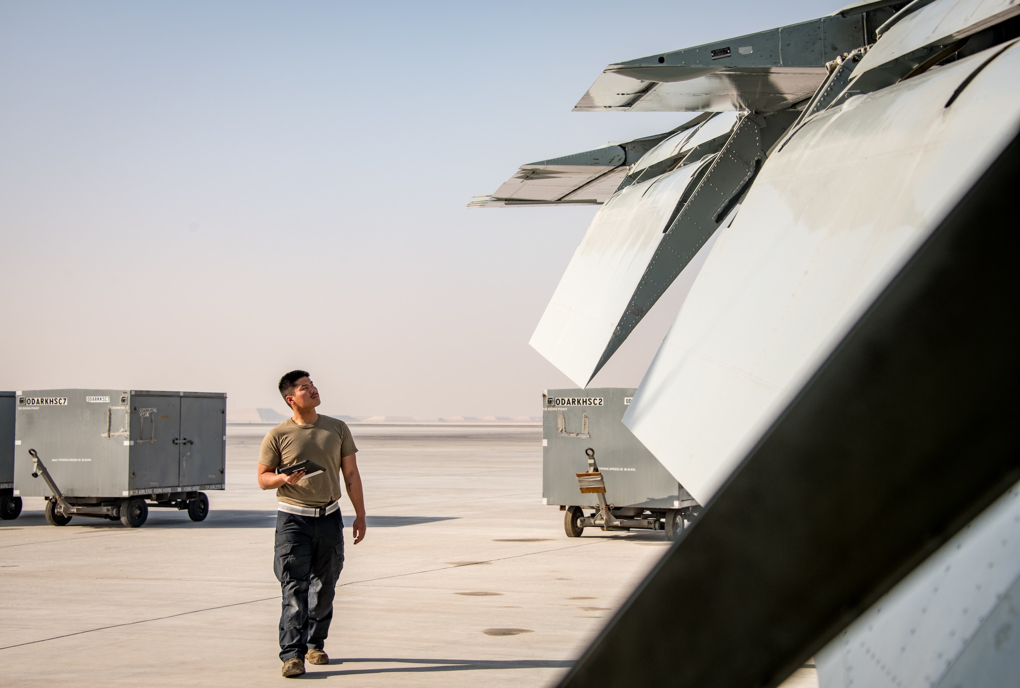 A man inspects the wing of an aircraft on a flightline