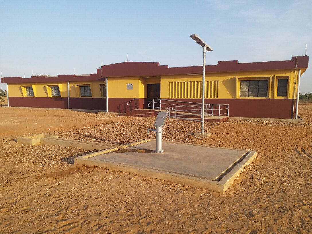 A recently completed health clinic, with a water well hand pump on a concrete pad and a solar powered light pole seen in the foreground, is seen here in the remote village of Money in Benin in Africa. The clinic and various associated facilities also built comprise one of two similar clinic projects recently completed by the U.S. Army Corps of Engineers in that region of Benin through funding from AFRICOM and coordinated closely with the U.S. State Department.