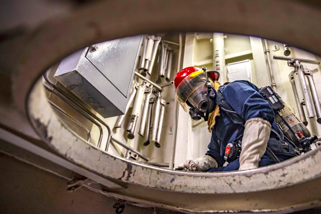 A sailor looks down through a large round hole.