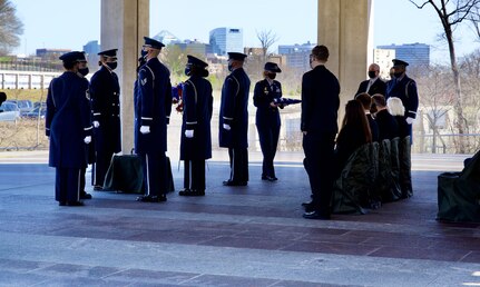 U.S. Air Force Col. Erica Rabe, Joint Base Anacostia-Bolling and 11th Wing vice commander, presents a flag to the family of U.S. Air Force Lt. Col. Bruce Burns as the United States Honor Guard Pallbearers stand at attention as part of modified military funeral honors with funeral escort in Section 82 of Arlington National Cemetery, Arlington, Virginia, March 22, 2021. Burns served in the Air Force from 1962 to 1982. His spouse, Janet Burns, received the flag from his service. The funeral was an historic occasion for the United States Honor Guard, with the largest female presence on a pallbearers team in Air Force history. (U.S. Air Force photo by Tech. Sgt. Katie Edelman)