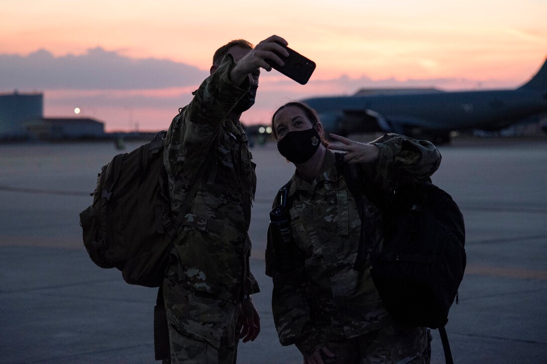 Two airmen take a selfie near aircraft.