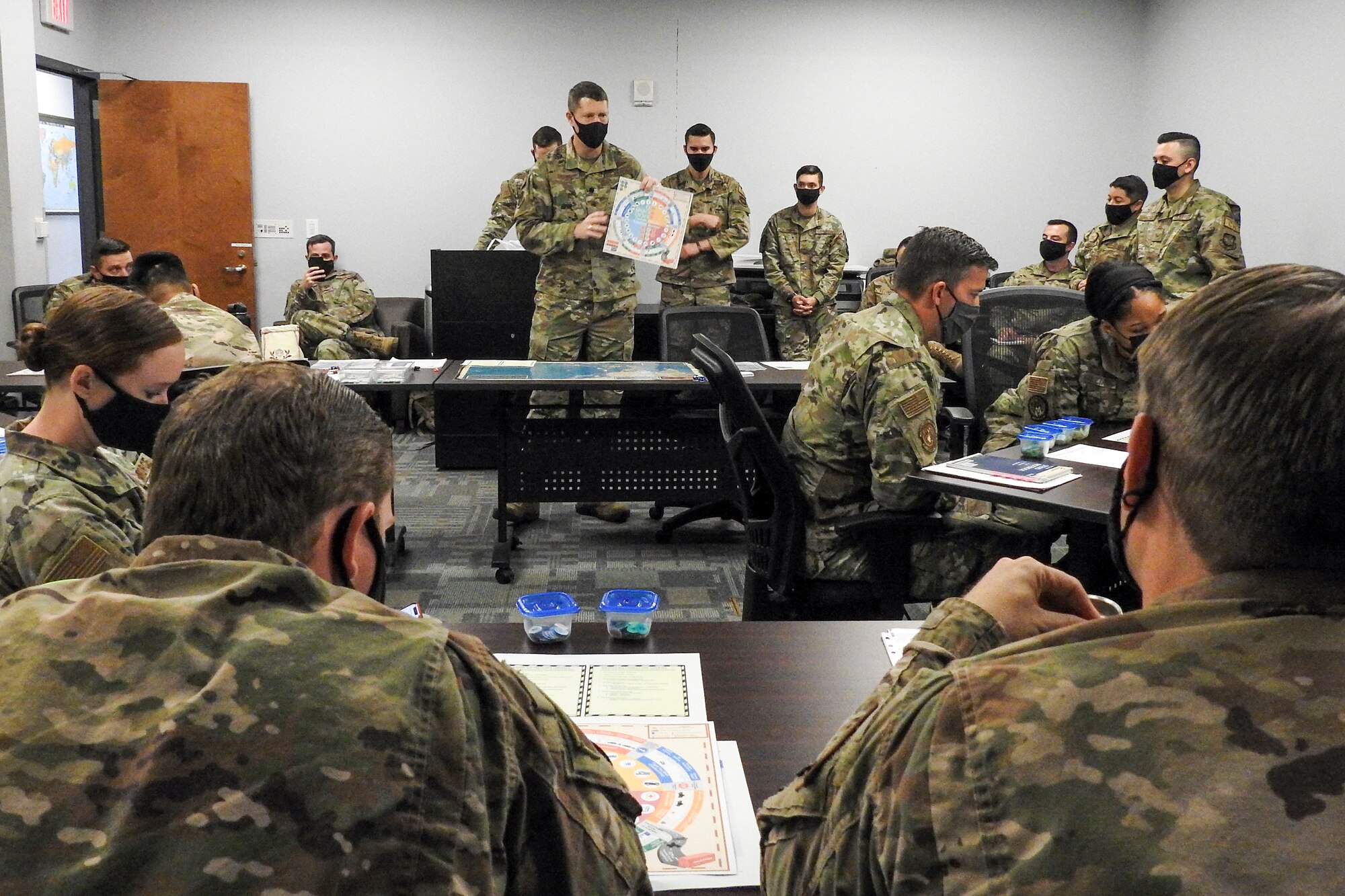 Twenty-five Airmen from various units within the 621st Contingency Response Wing listen to instructions on how to play a prototype board game called “Kingfish ACE” March 26, 2021, at Travis Air Force Base, California. U.S. Air Force Lt. Col. Troy Pierce, while attending the Marine Corps War College, created the game as part of his final project at the college. (U.S. Air Force photo by Senior Airman Chad Kotce)