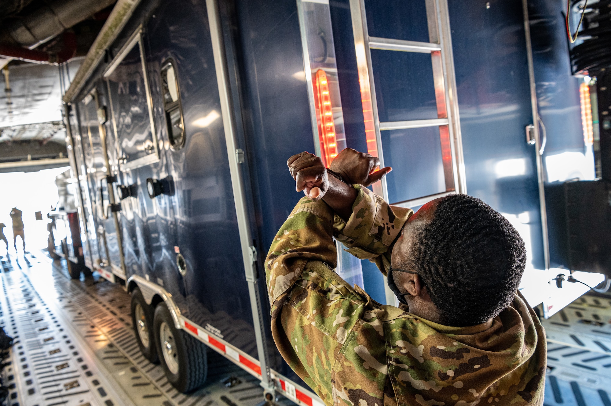 Staff Sgt. John Shauri, 3rd Airlift Squadron loadmaster, marshals a Delaware Army National Guard trailer onto a C-17 Globemaster III during joint training at Dover Air Force Base, Delaware, March 29, 2021. The training focused on providing rapid global airlift through the integration of U.S. Air Force Airmen and Delaware National Guard Soldiers. (U.S. Air Force photo by Senior Airman Christopher Quail)