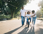 Parents help child ride bicycle