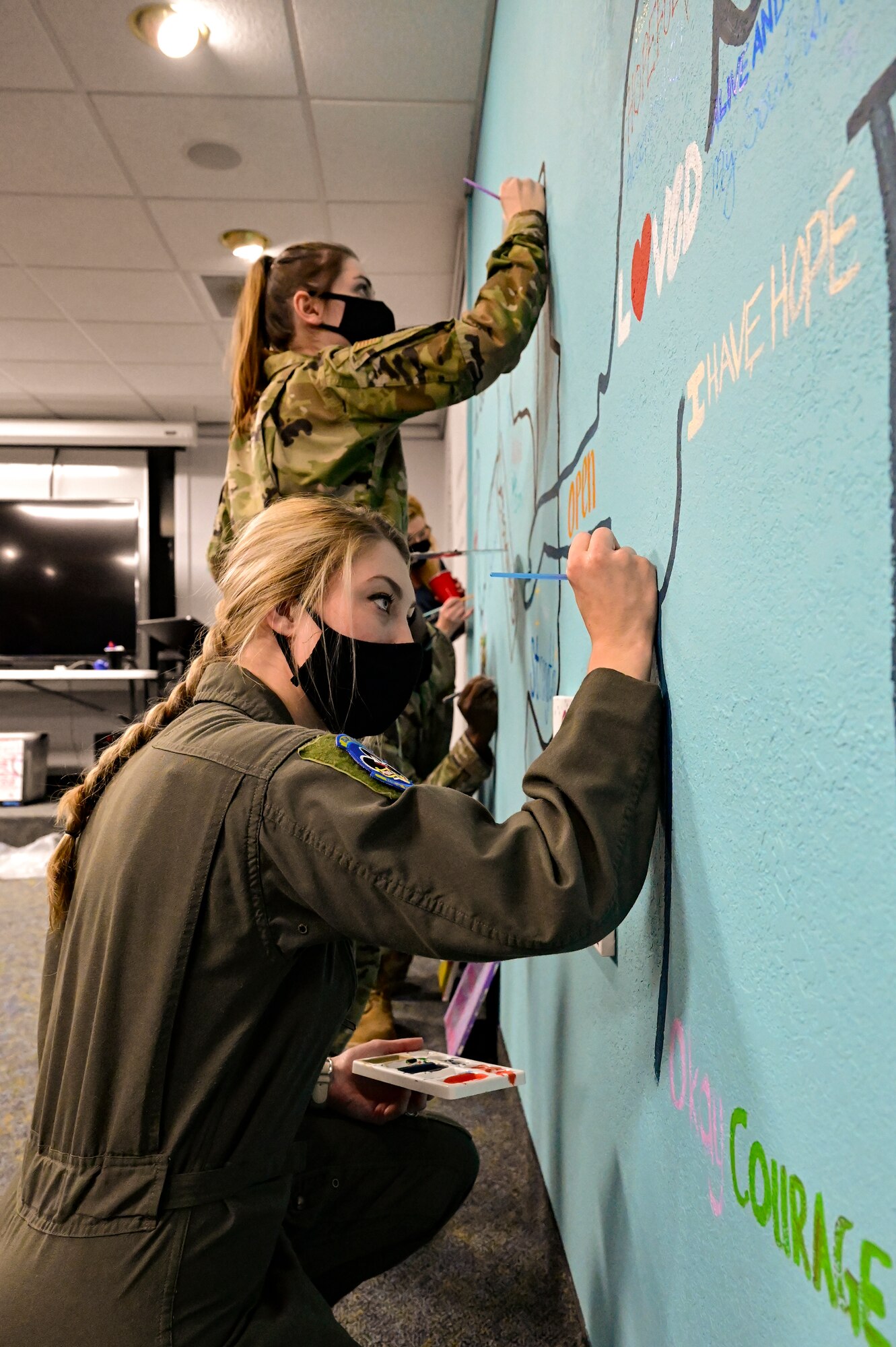 two airmen paint a mural