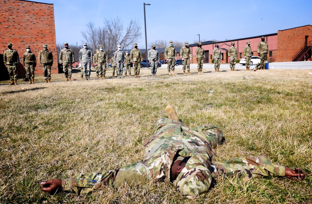 In foreground, an Airman waits to be found in a grassy area during training.  The 932nd Force Support Squadron conducted hands-on Search and Recovery training March 8, 2021, at Scott Air Force Base, Ill.  "Per AFI 34-501, FSS professionals are trained to respond in the event of an actual mishap involving Air Force assets or Air Force Personnel.  This training is integral to FSS home station readiness training and is one of the largest collective functional training requirements for Force Support professionals," said Maj. Jennifer Fillmore, commander of FSS.  "Our Sustainment Flight, led by Maj. Christine Froeber and Senior Master Sgt. Jennifer Royer, led us in accomplishing training for the majority (30+ personnel/75%) of the unit," she added.  (U.S. Air Force photo by Lt. Col. Stan Paregien)