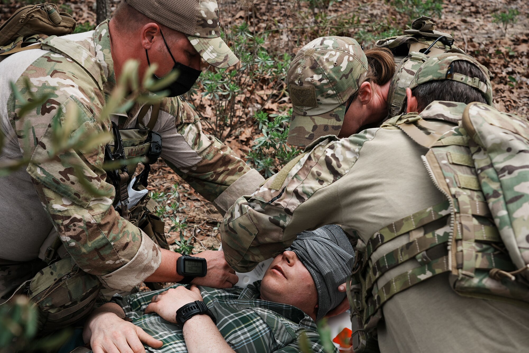 Three Airmen provide medical care to a casualty.