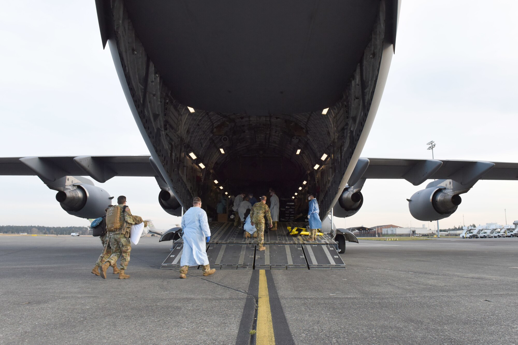 An aeromedical evacuation team from the 775th Expeditionary Aeromedical Evacuation flight at Travis Air Force Base, California, and other medical professionals from Madigan Army Medical Center, board a C-17 Globemaster III at Joint Base Lewis-McChord, Washington, March 31, 2021. The team airlifted a COVID-19 patient with severe symptoms to San Antonio Army Medical Center in Texas. (U.S. Air Force photo by Senior Airman Mikayla Heineck)
