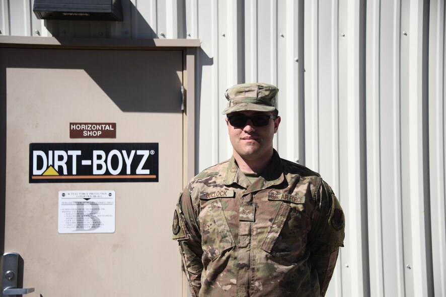 An Airman stands in front of his squadron door posing for a picture.