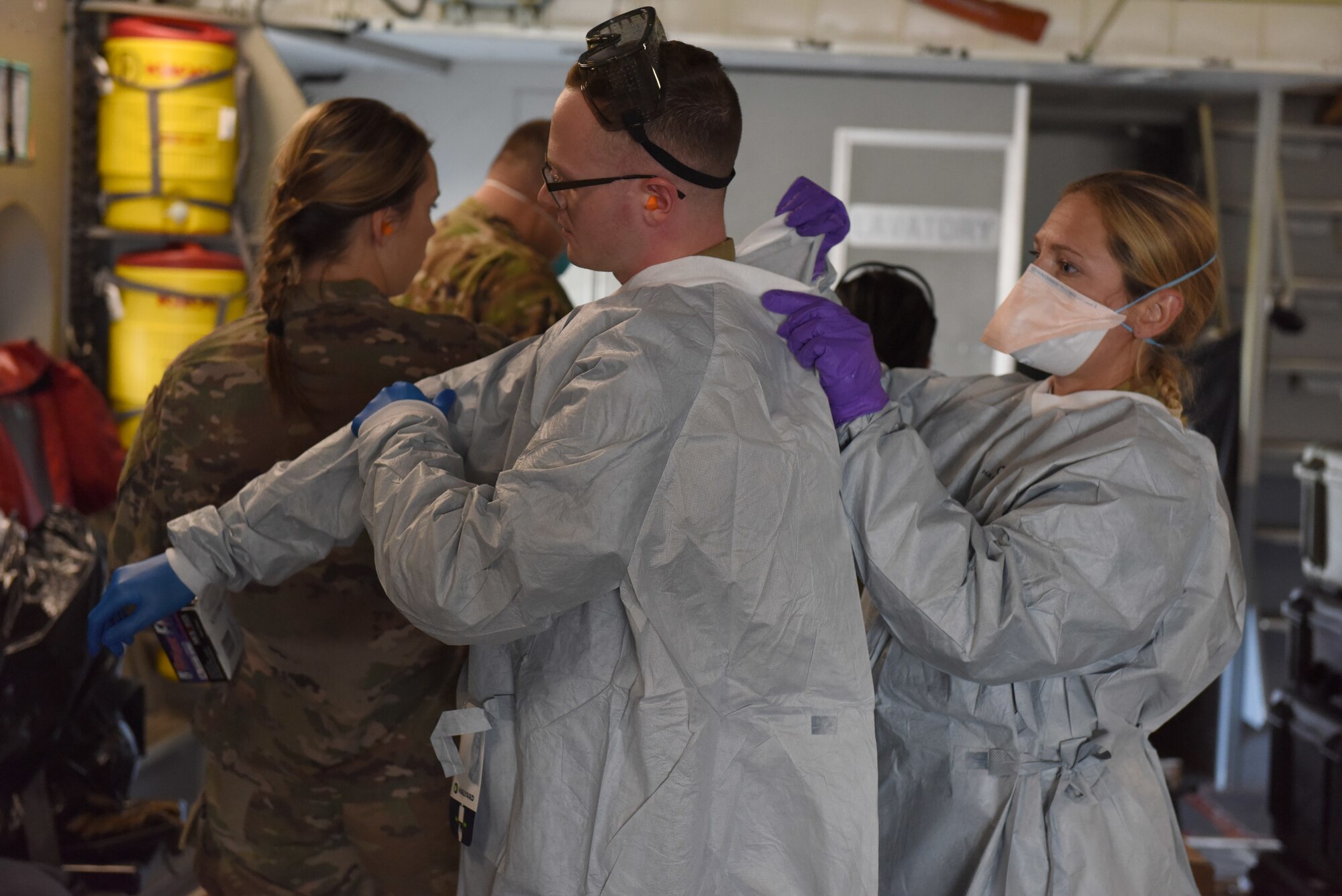 U.S. Air Force Airmen from the 775th Expeditionary Aeromedical Evacuation flight from Travis Air Force Base, California, don personal protective equipment aboard a C-17 Globemaster III on Joint Base Lewis-McChord, Washington, March 31, 2021. Aeromedical evacuation personnel are responsible for caring for medical patients in-flight and preparing a safe environment for them as well as the aircrew. (U.S. Air Force photo by Senior Airman Mikayla Heineck)