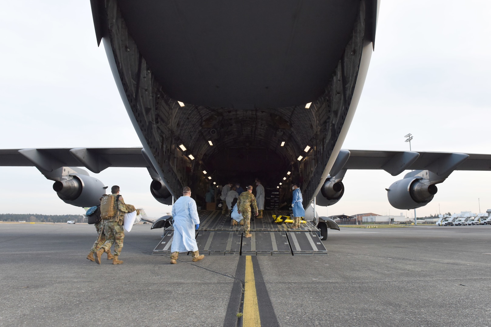 An aeromedical evacuation team from the 775th Expeditionary Aeromedical Evacuation flight at Travis Air Force Base, California, and other medical professionals from Madigan Army Medical Center, board a C-17 Globemaster III at Joint Base Lewis-McChord, Washington, March 31, 2021. The team airlifted a COVID-19 patient with severe symptoms to San Antonio Army Medical Center in Texas. (U.S. Air Force photo by Senior Airman Mikayla Heineck)