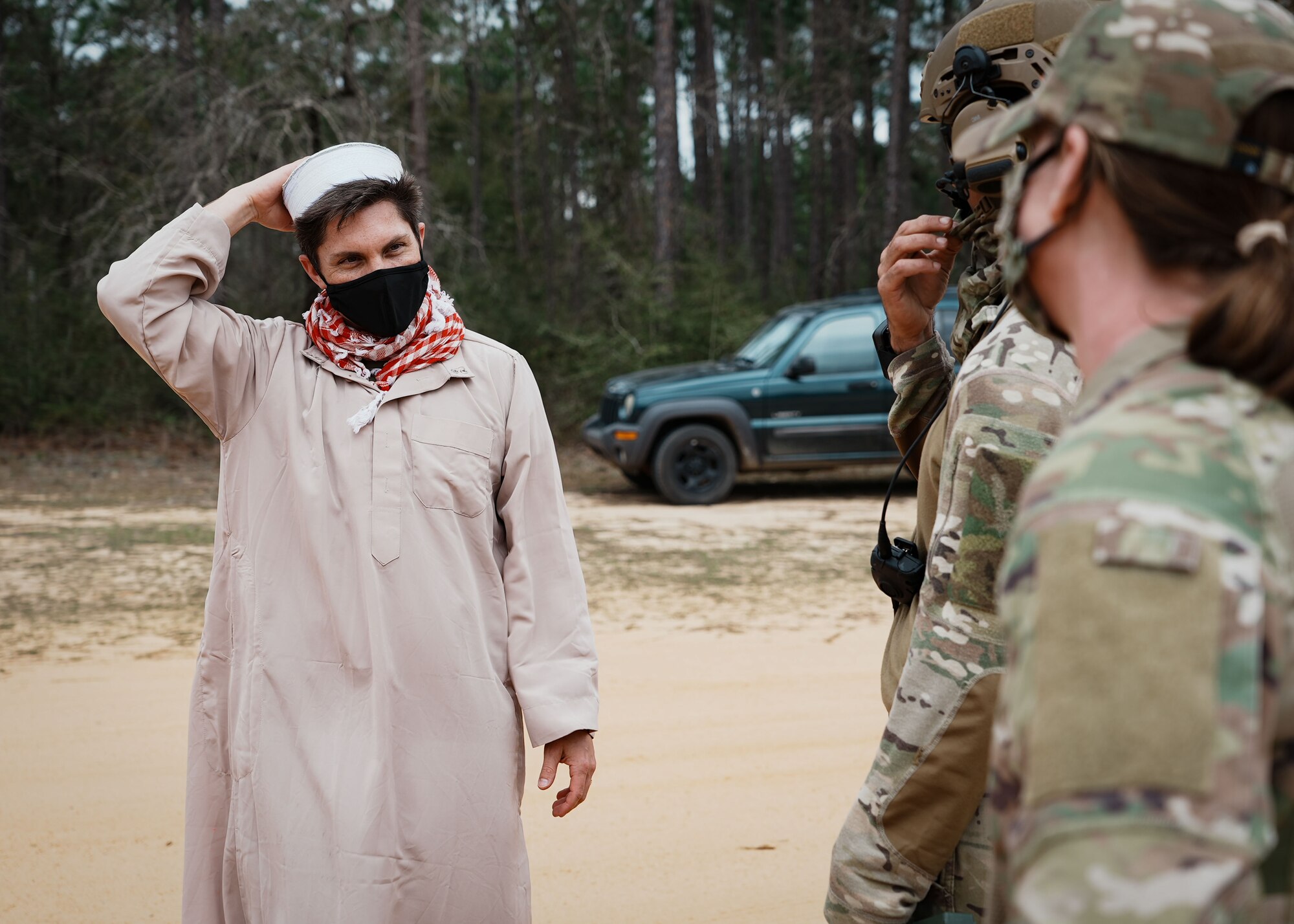 Two Airmen speak to a man wearing a tunic.