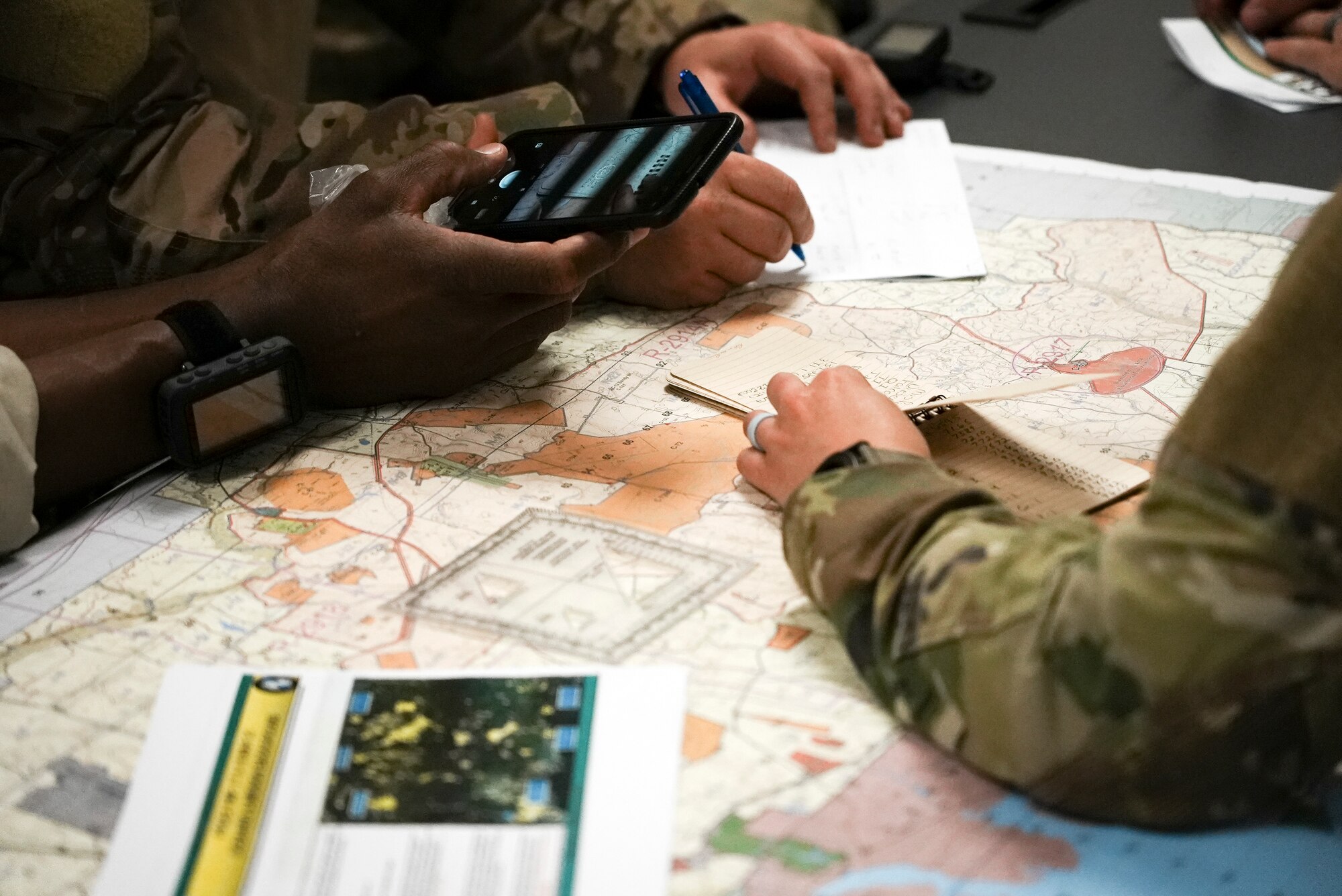 Three Airmen take notes on map.