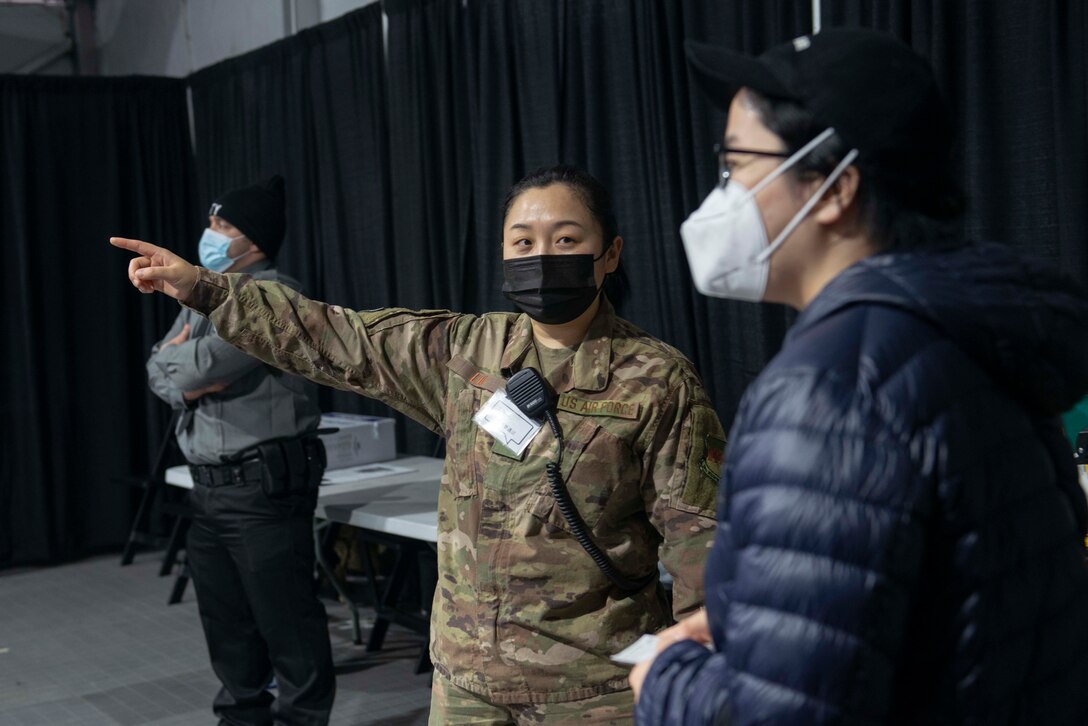 Senior Airman Can Liu, from Queens, N.Y., and a 335th Expeditionary Medical Operations Squadron general purpose Airman, ushers a community member at the state-led, federally-supported Medgar Evers College Community Vaccination Center in Brooklyn, N.Y., March 24, 2021. Liu, who is deployed from the 20th Civil Engineer Squadron out of Tyndall Air Force Base, Fla., was born in Fushun, China, is fluent in Mandarin. Liu is able to translate for Chinese community members who have questions while receiving their COVID-19 vaccination. U.S. Northern Command, through U.S. Army North, remains committed to providing continued, flexible DoD support to the Federal Emergency Management Agency as part of the whole-of-government response to COVID-19. (U.S. Air Force photo by Tech. Sgt. Ashley Nicole Taylor)