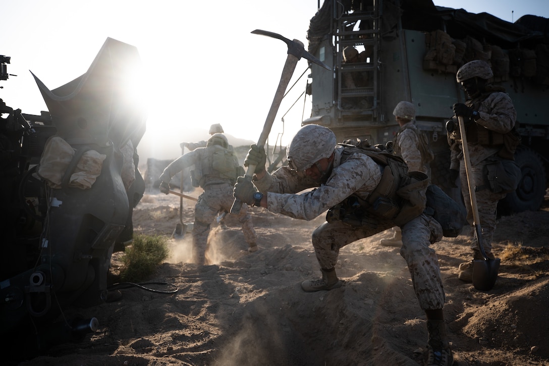 U.S. Marine Corps Pfc. Aristeo Morales, a field artillery cannoneer with Battery A, 1st Battalion, 11th Marine Regiment, 1st Marine Division, digs an entrenchment for an M777 towed 155 mm howitzer during a live-fire defense simulation at the Marine Corps Air Ground Combat Center in Twentynine Palms, Calif., March 30, 2021. The Marines dug these entrenchments during a live-fire defense training evolution to brace the guns as they fired on a notional enemy in defense of their position.