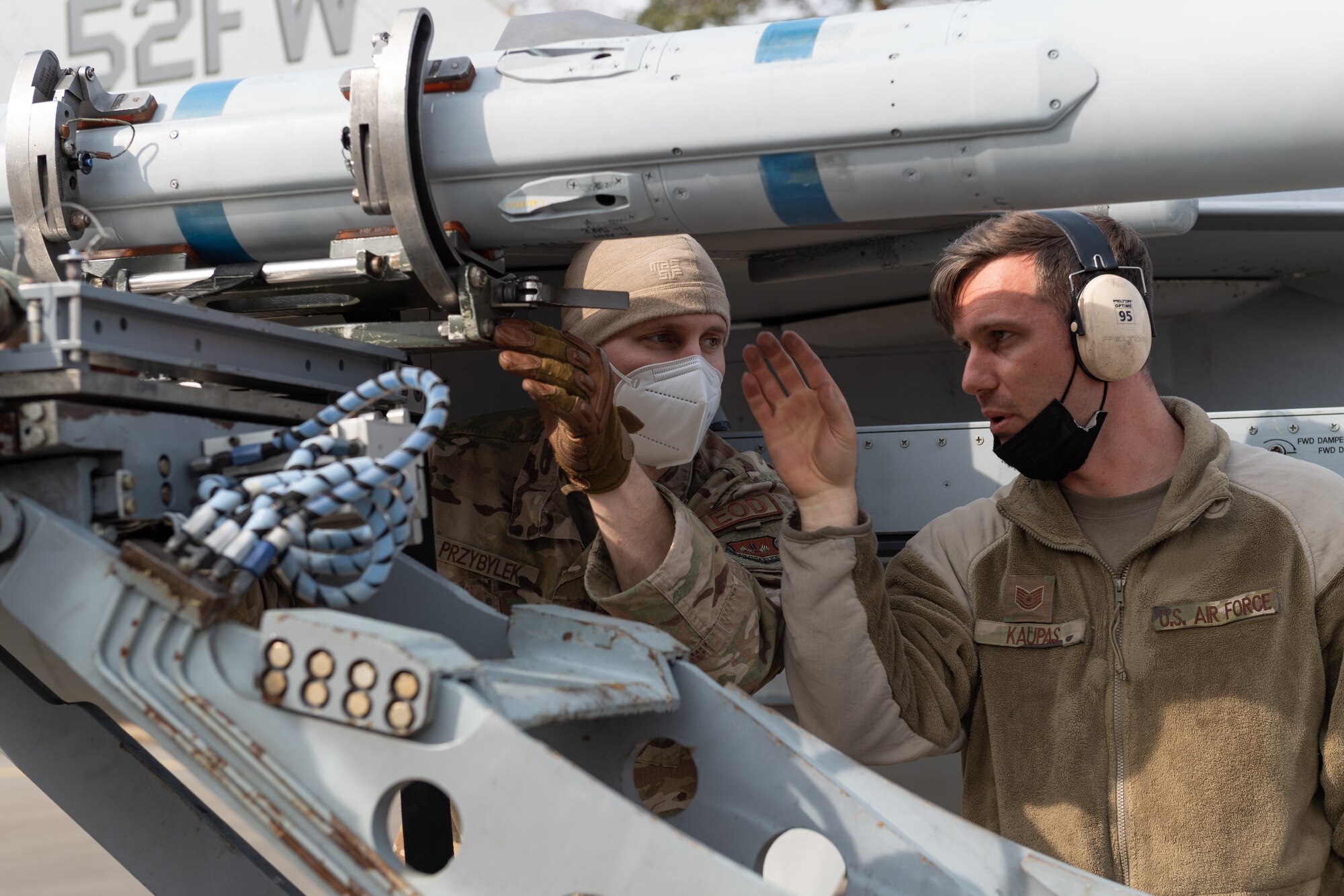 U.S. Air Force Tech. Sgt. Joseph Kaupas (right), 52nd Aircraft Maintenance Squadron Weapons Expediter instructs U.S. Air Force Staff Sgt. Thomas Przybylek, 52nd Explosive Ordnance Disposal technician (left), how to place a munition on an U.S. Air Force F-16 Fighting Falcon at an Agile Combat Employment exercise at Ramstein Air Base Germany, March 25, 2021. The exercise called for Spangdahlem Airmen to support operations in a simulated adverse environment with minimal personnel, resources and time. (U.S. Air Force photo by Senior Airman John Wright)