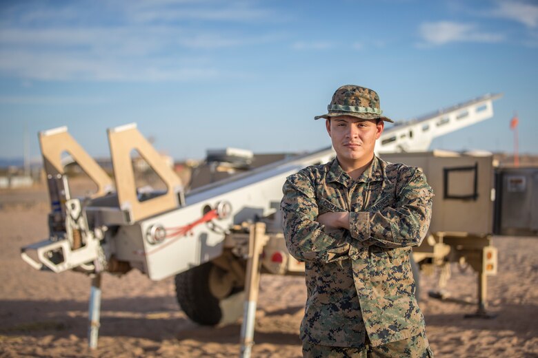 U.S. Marine Corps Lance Cpl. Oscar Cruz-Acencio, an unmanned aircraft system technician, with Marine Unmanned Aerial Vehicle Squadron (VMU) 1 stands in front of a RQ-21 "Blackjack" launch system on Canon Air Defense Complex in Yuma, Arizona, Nov. 5, 2020. The RQ-21 is designed to support Marine Corps mission readiness by providing forward reconnaissance without having to put Marine Corps personnel at risk.(U.S. Marine Corps photo by Lance Cpl. John Hall)
