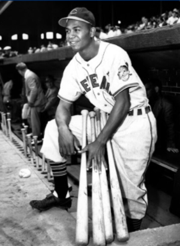 A baseball player poses for a photo at the edge of the dugout.