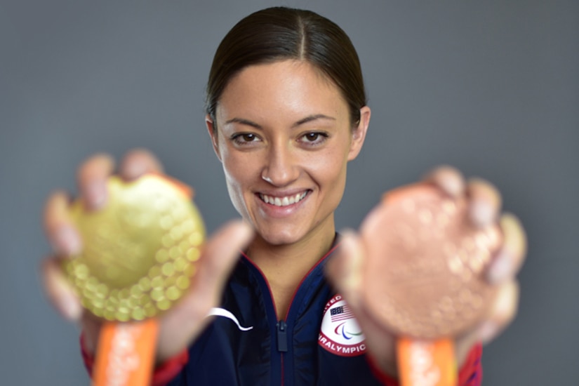 A soldier holds out two medals.