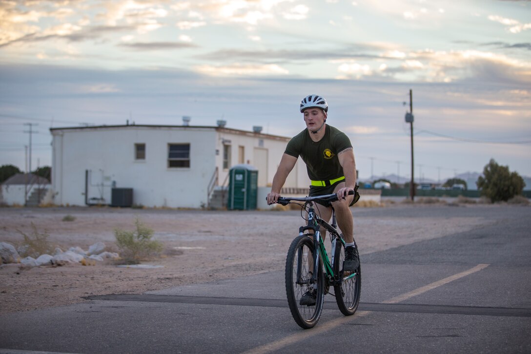 U.S. Marine Corps Corporal Ivan Wilkins, a corrections specialist, with Headquarters and Headquarters Squadron (H&HS), races a bicycle while competing in the monthly squadron competition on Marine Corps Air Station Yuma, Ariz., Nov. 6, 2020.