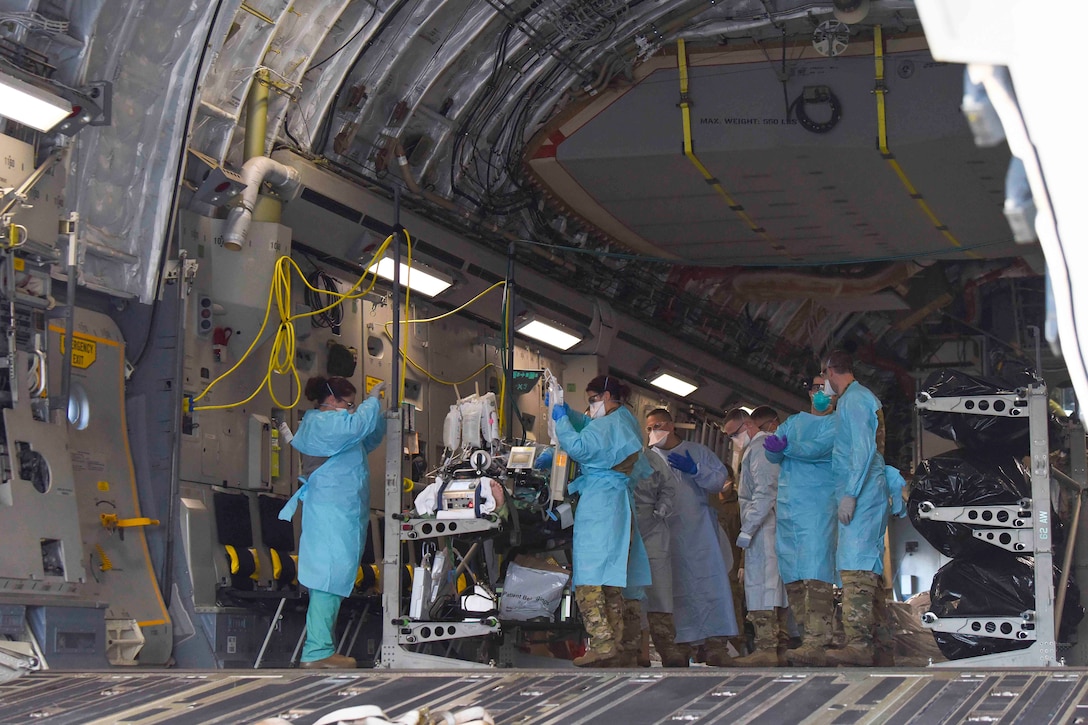 A group of airmen work on a patient inside an aircraft.