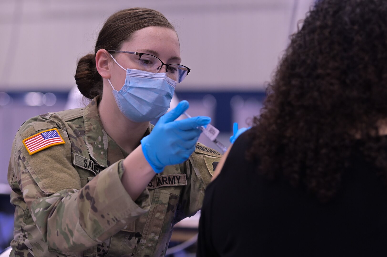 Illinois Army National Guard Spc. Emily Salmon, 2123 Forward Support Company combat medic, administers the COVID-19 vaccine in the South Suburban College gym, South Holland, Illinois, Feb. 25, 2021. Guard members were called on to support COVID-19 relief efforts.