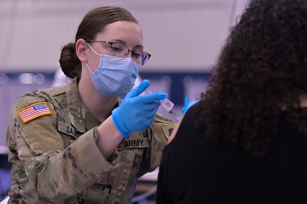 Illinois Army National Guard Spc. Emily Salmon, 2123 Forward Support Company combat medic, administers the COVID-19 vaccine in the South Suburban College gym, South Holland, Illinois, Feb. 25, 2021. Guard members were called on to support COVID-19 relief efforts.