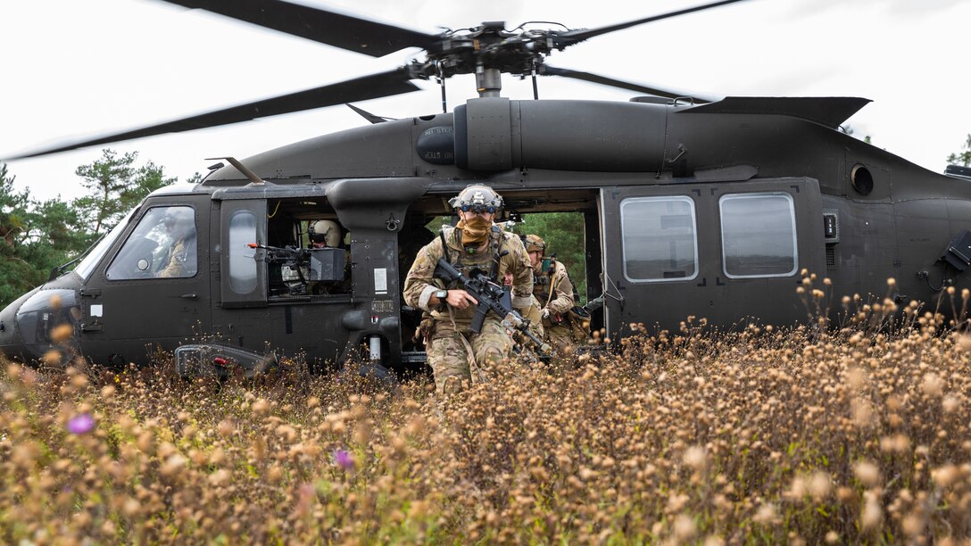 Troops exit a helicopter.