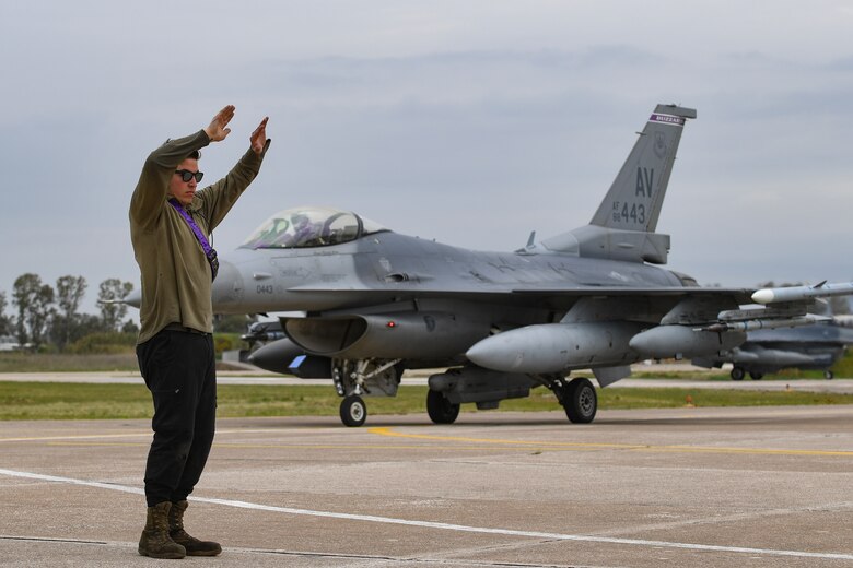 An Airman from the 31st Fighter Wing marshals a U.S. Air Force F-16 Fighting Falcon from the 31st FW after landing at Andravida Air Base, Greece, April 6, 2021. The 31st FW arrived in Greece to participate in INIOCHOS 21. INIOCHOS 21 is an annual Hellenic air force-led joint exercise focusing on interoperability between different countries. (U.S. Air Force photo by Airman 1st Class Thomas S. Keisler IV)
