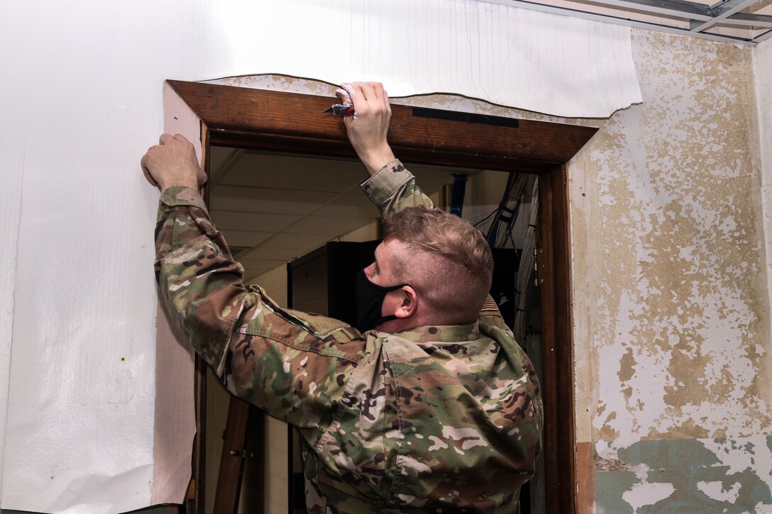 Tech. Sgt. Jason Goss, 28th Civil Engineer Squadron structural craftsman, peels off wall paper to put Joint compound on a wall at Dyess Air Force Base, Texas, Mar. 9, 2021. Joint compound helps repair cracks and holes in existing drywall and plaster surfaces. (U.S. Air Force photo by Staff Sgt. David Owsianka)