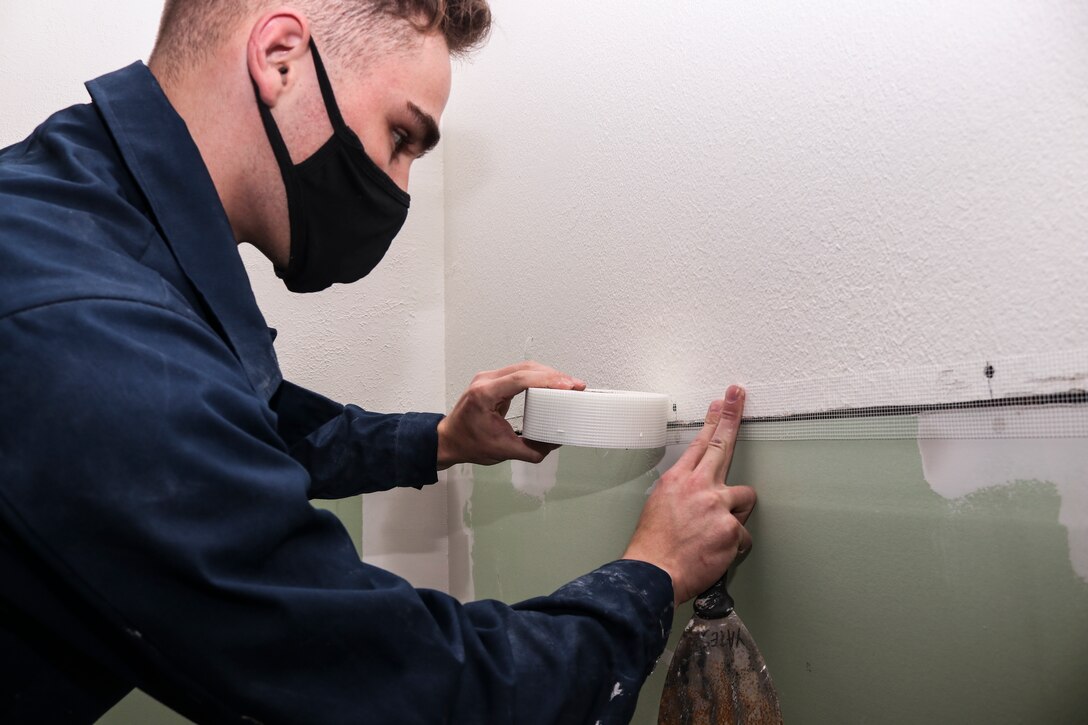 Airman Brody Yates, 628th Civil Engineer Squadron structural apprentice, places mesh tape on a wall to fill in gaps to place joint compound in a room at Dyess Air Force Base, Texas, Mar. 9, 2021. Members of CES’s from Travis AFB, Calif., Charleston AFB, S.C., F.E. Warren AFB, Wyo., and Minot AFB, N.D., aided Dyess personnel with repairing a building affected by winter weather damage. (U.S. Air Force photo by Staff Sgt. David Owsianka)