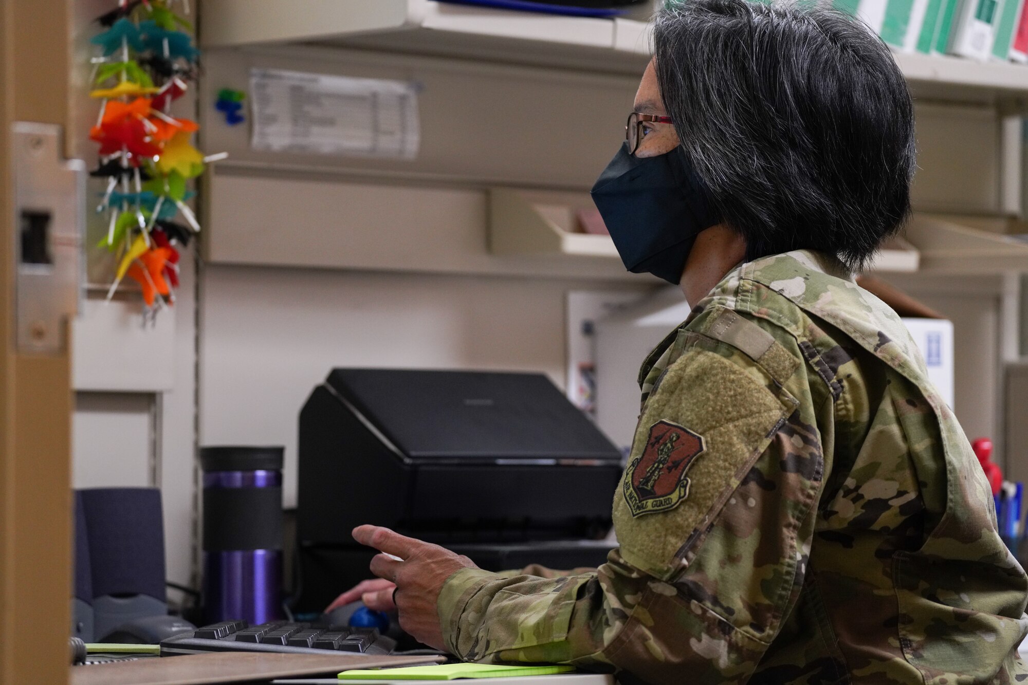 A U.S. Air National Guard woman sits at their desk typing updates into medical profiles on a computer inside a medical vaccination storage room.