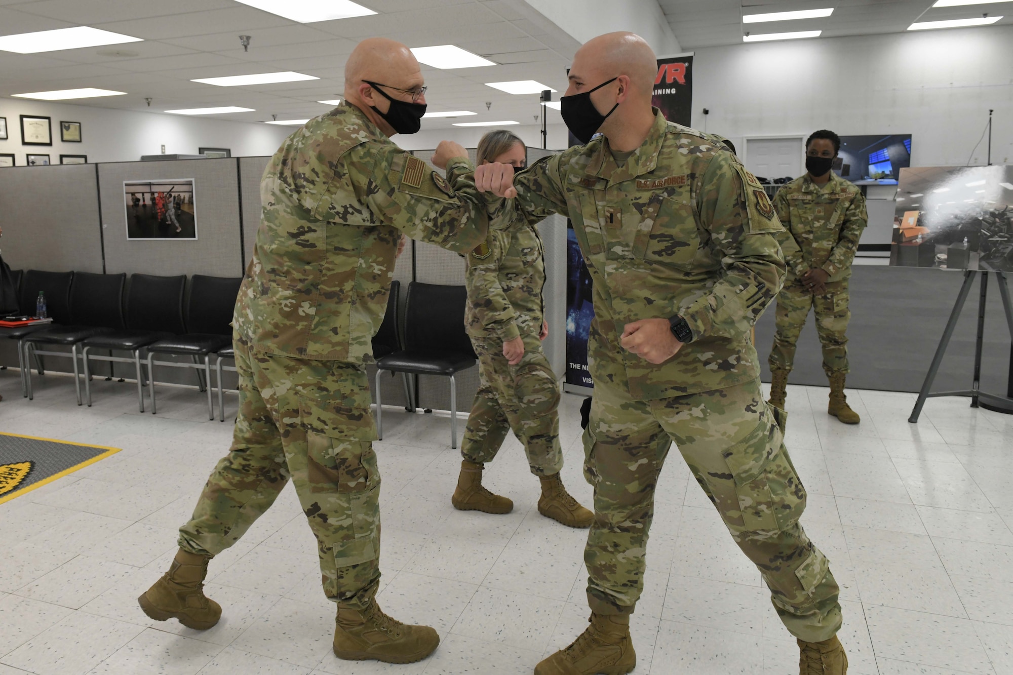 Photo shows the general and the Airman elbow bumping.