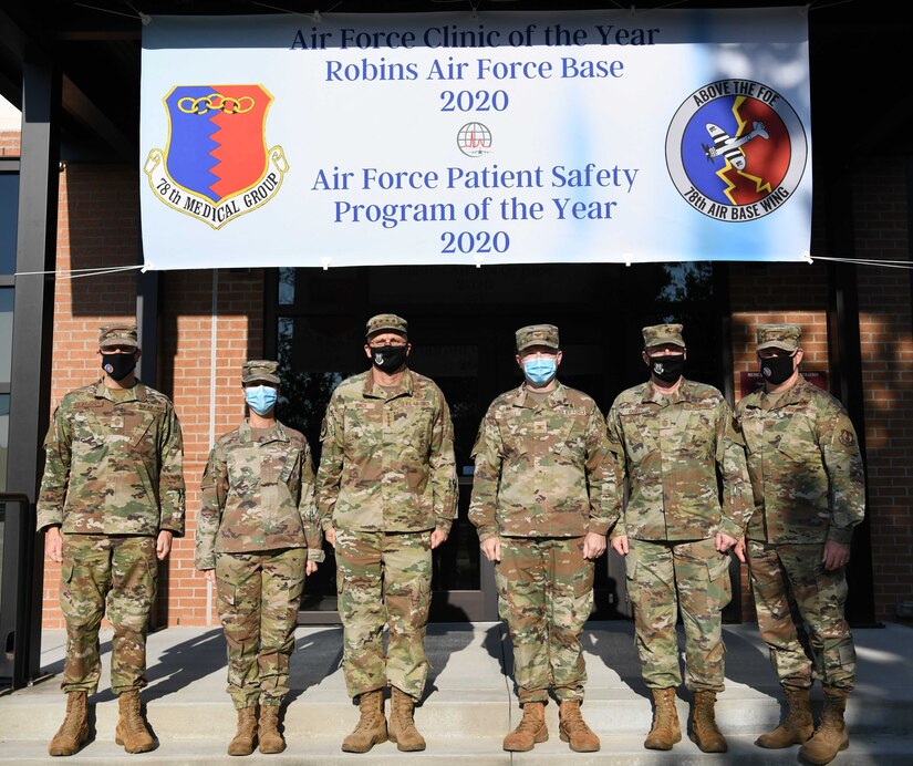 Photo shows group standing in front of banner stating the MDG is best in the Air Force.