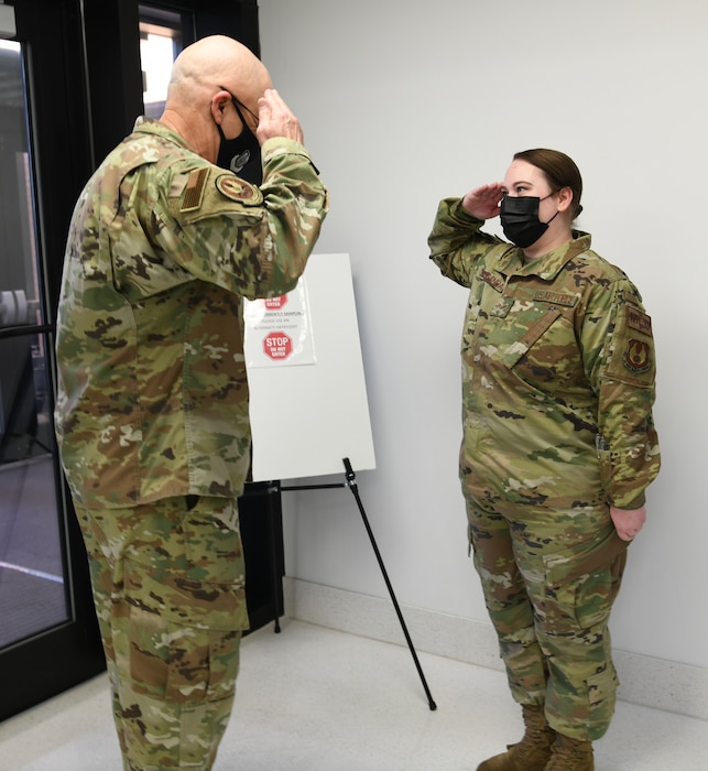 Photo shows the general and Airman saluting each other.