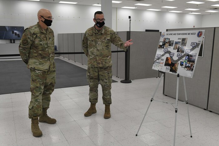 Photo shows two men looking at an information board on an easel.