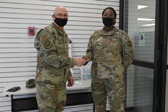 Photo shows the general giving his coin to the Airman in an entryway.