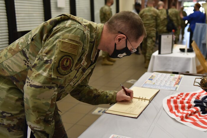 Photo shows the chief signing a book on a table.