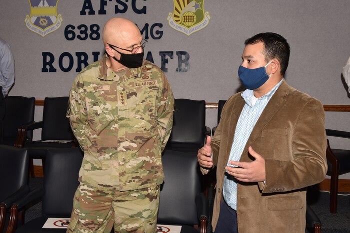 Photo shows the two talking in a conference room.
