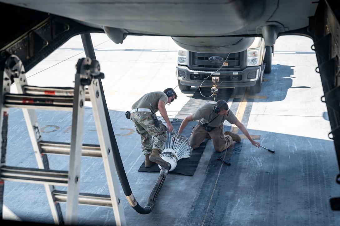 Two members of the 380th Expeditionary Aircraft Maintenance Squadron attach a drogue to a truck.