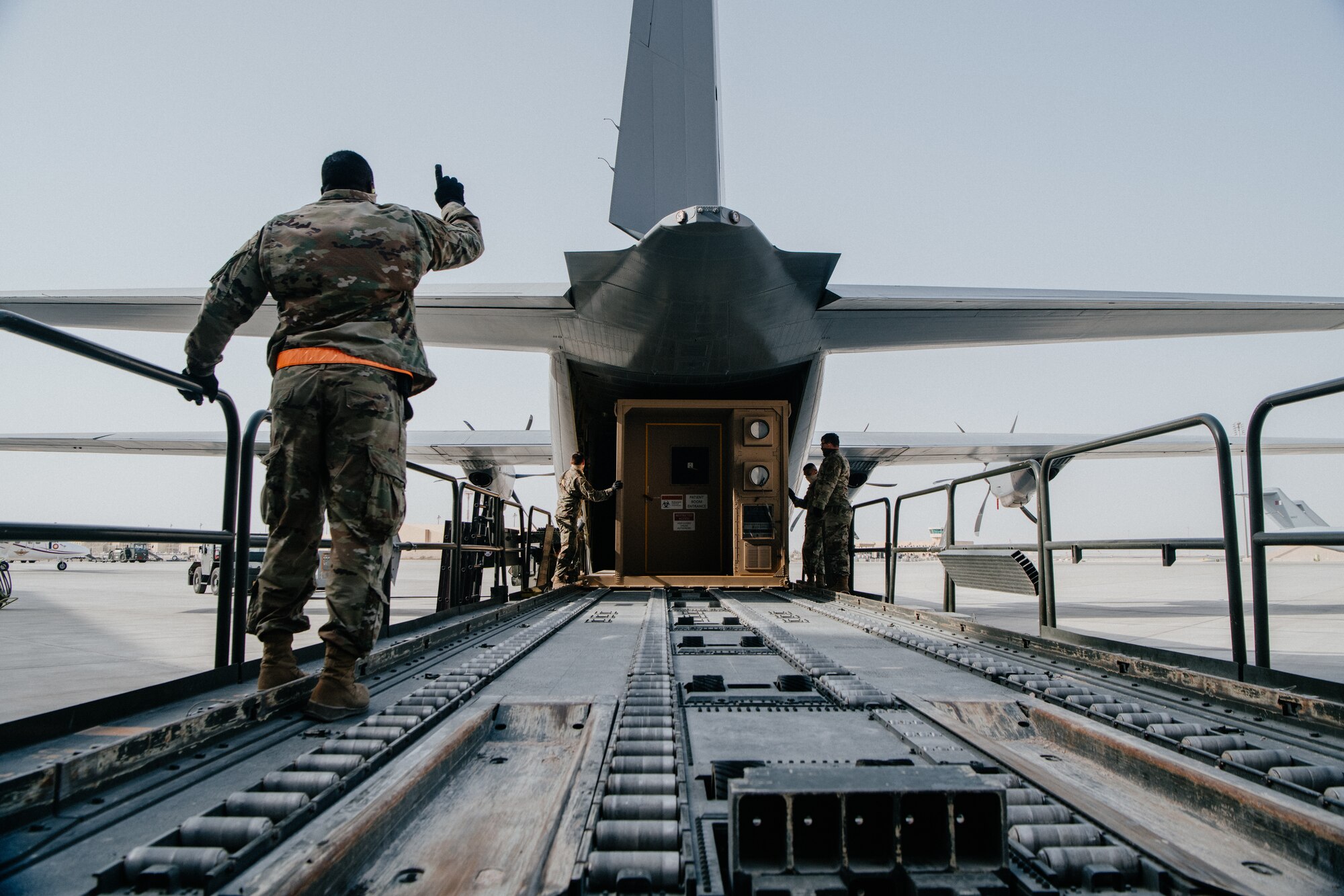 airman gives thumbs up as conex is loaded onto plane