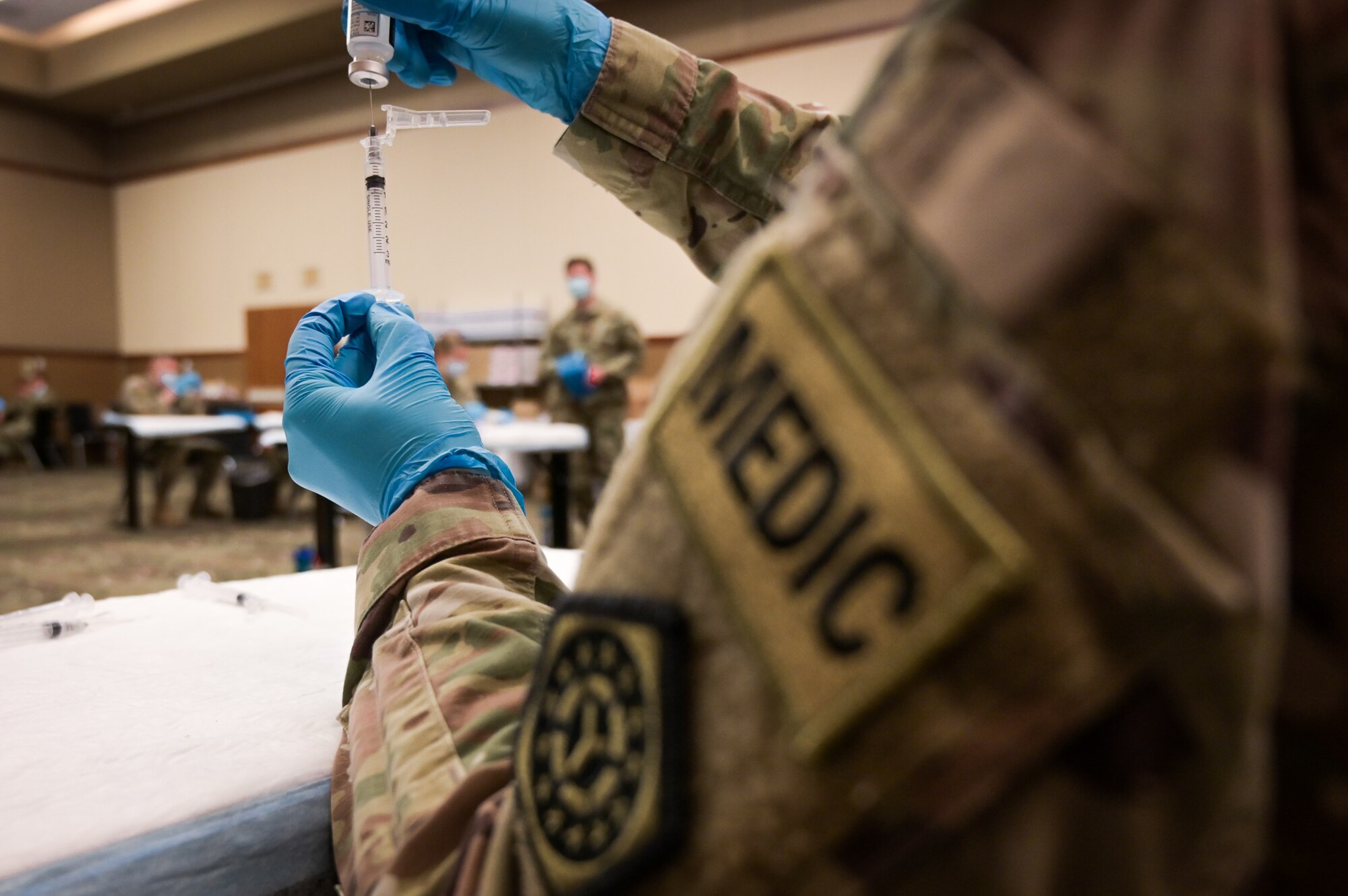 U.S. Army combat medic draws the COVID-19 vaccine into a syringe in the Tinley Park Convention Center in Tinley Park, Illinois, February 26, 2021. Medical professionals draw the vaccine as a part of the daily process to match the numbers of vaccines prepared with the number of patients receiving it. (U.S. National Guard photo by Staff Sgt. Aaron Rodriguez)