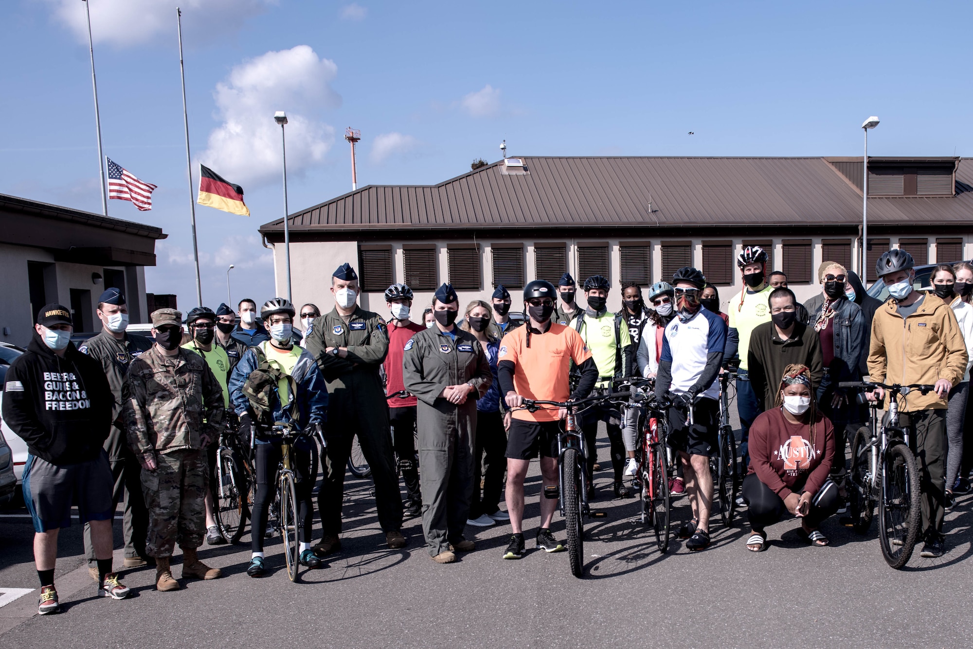 People stand for a group photo, several of them have bicycles.